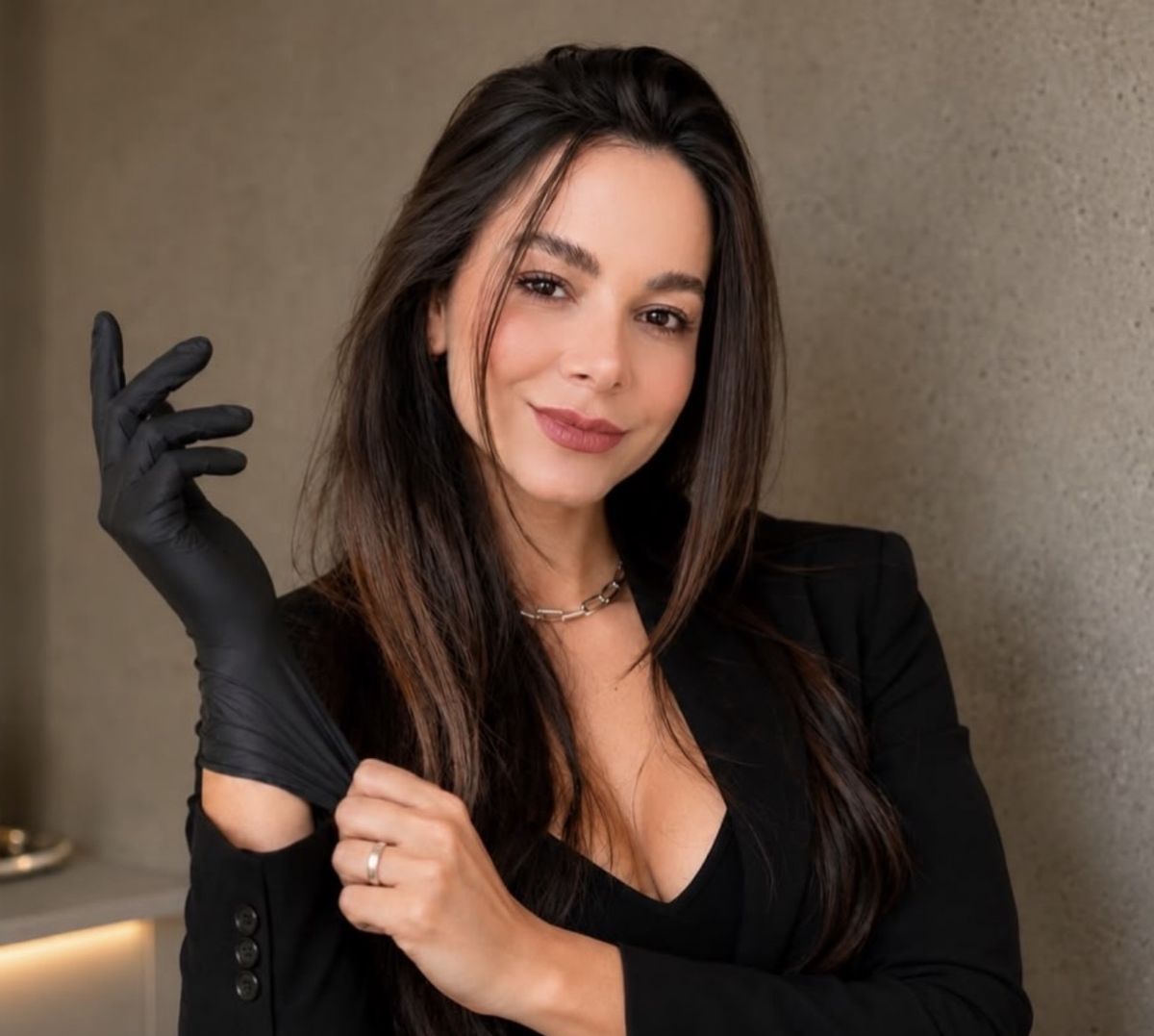 Dra. Jéssica Gomes de blazer preto, calçando a luva para atender